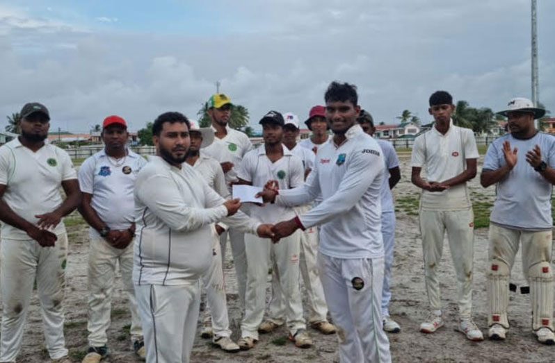 Yuraj Khemraj (left) presents the envelope to Aaron Beharry in the presence of his teammates.