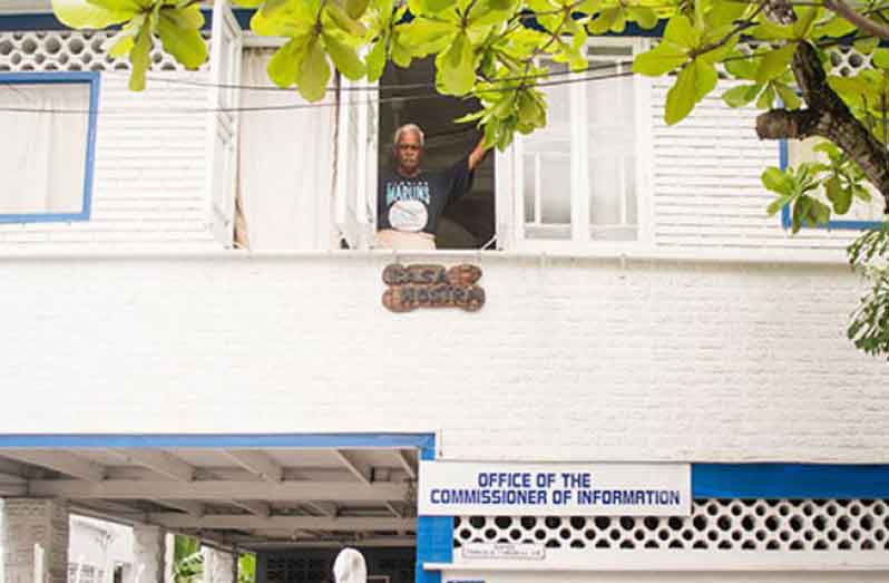 “Justice Charles Ramson peers out his East Street ‘place of operation’ marked by two juxtaposed signs of “Our Home” in Latin, and “Office of the Commissioner of Information” (Samuel Maughn/Guyana Chronicle/2016)