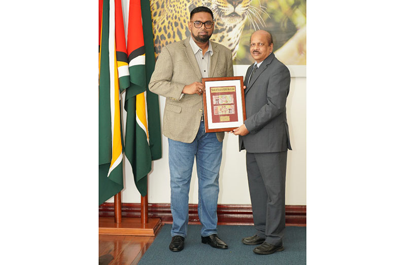 Governor of the Bank of Guyana, Dr Gobind Ganga (right) presents the new note to President Dr Irfaan Ali (Photo: Office of the President)