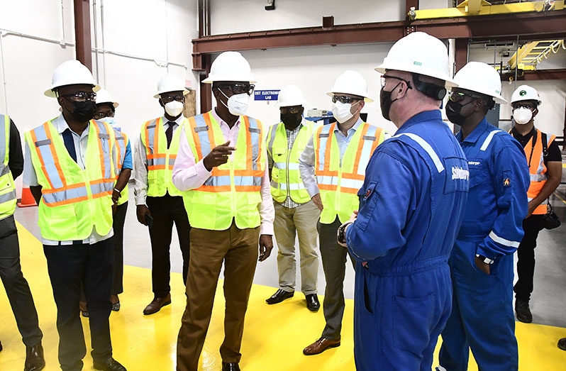 Labour Minister, Joseph Hamilton (second from left) speaking with Schlumberger employees, as Managing Director of Schlumberger GTC, Ernesto Cuadros (fourth from right), looks on