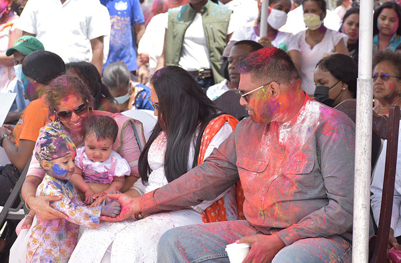 President Dr Irfaan Ali and First Lady Arya Ali, interact with a child during the Holi celebration (Elvin Croker photo)