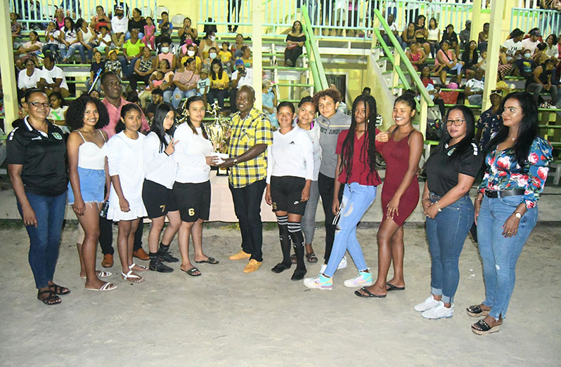 Leader of the Opposition, Mr Aubrey Norton hands over the winning prize to AX Galaxy captain Lisa Pereira, in the presence of some teammates and dignitaries