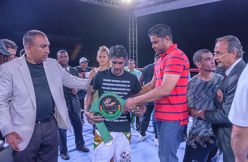 Minister of Sports Charles Ramson Jr (right ) and Promoter Aleem Hussain (left ) present the championship belt to Guyanese Elton Dharry