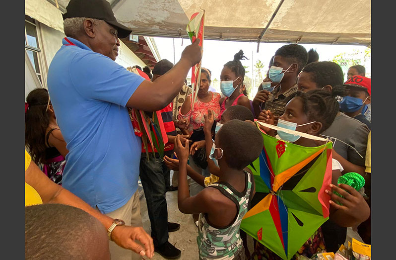 Minister of Home Affairs Robeson Benn distributing kites at the Sophia Health Centre on Saturday