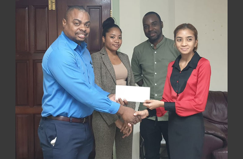 Representative of NHFS, Kamari John, (extreme right) hands over a cheque to organisers Edison Jefford (extreme left) and Esan Griffith (second right) during a simple handing-over ceremony at NHFS Headquarters on Croal Street.