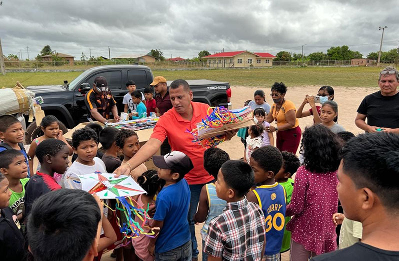Minister of Housing and Water, Collin Croal distributes kites to children in Tabatinga