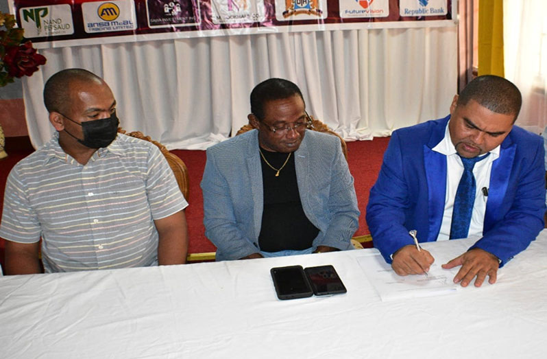 President of the Berbice Chamber of Commerce and Development Association, Ryan Alexander signs the agreement while the Commissioner of Police (ag), Clifton Hicken and Deputy Commissioner, Calvin Brutus look on