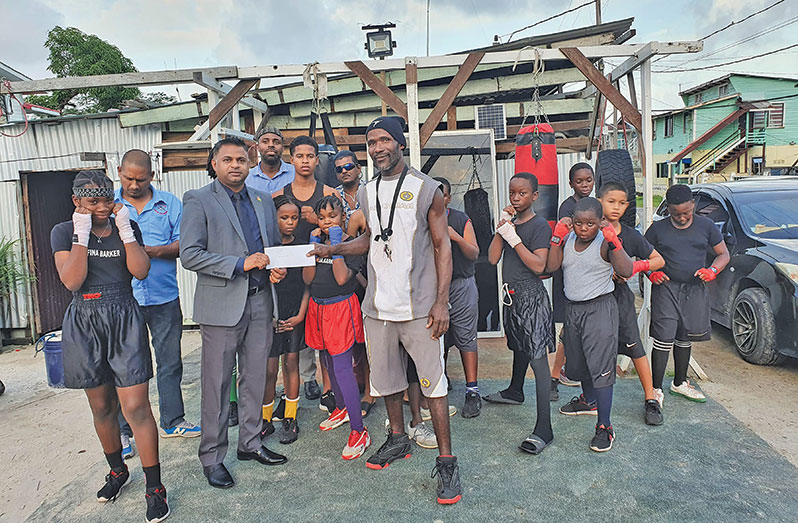 Minister Deodat Indar hands over the donation to the coach of  Pace and Power Boxing Gym, Clifton Baker