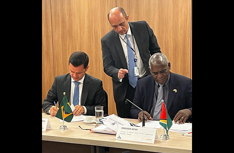 Home Affairs Minister, Robeson Benn, signs the agreement with a Brazilian official (Ministry of Home Affairs photo)