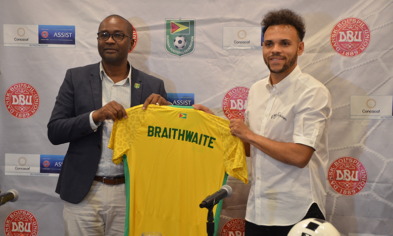 Guyana Football Federation President, Wayne Forde, hands over a ceremonial Golden Jaguars jersey to Denmark and Barcelona forward, Martin Braithwaite