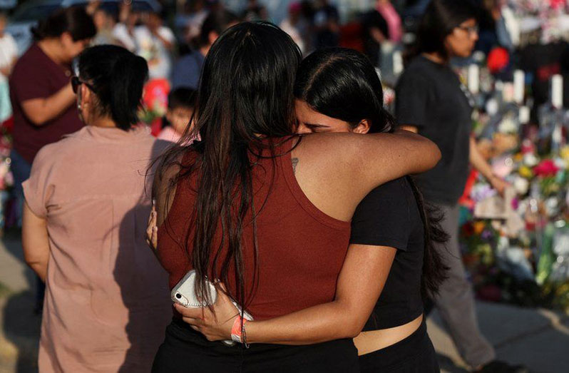 Women embrace at a memorial to those killed in the Uvalde mass shooting (BBC/Reuters photo)
