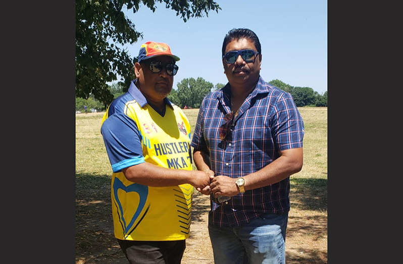 New York-based Guyanese Chin Singh (left) hands over the contribution to Anil Beharry