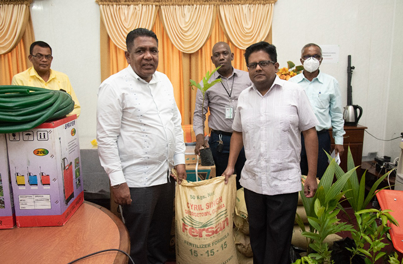 Agriculture Minister Zulfikar Mustapha and Senior Minister in the Office of the President with Responsibility for Finance, Dr Ashni Singh, hold a bag of fertiliser as others look on at the handing-over ceremony on Wednesday (Ministry of Finance photo)