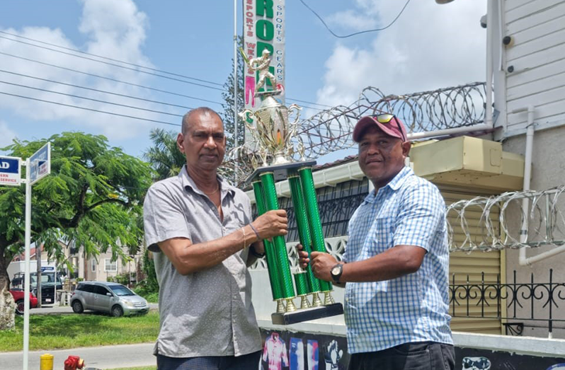 Essequibo Cricket Board Vice-President, Elroy Stephney (right) receiving the winner’s trophy from Ramesh Sunich of Trophy Stall