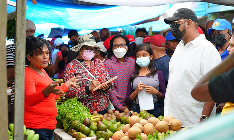 President, Dr Irfaan Ali and other officials listen to the concerns of a vendor at the Parika Market in April (Latchman Singh photo)