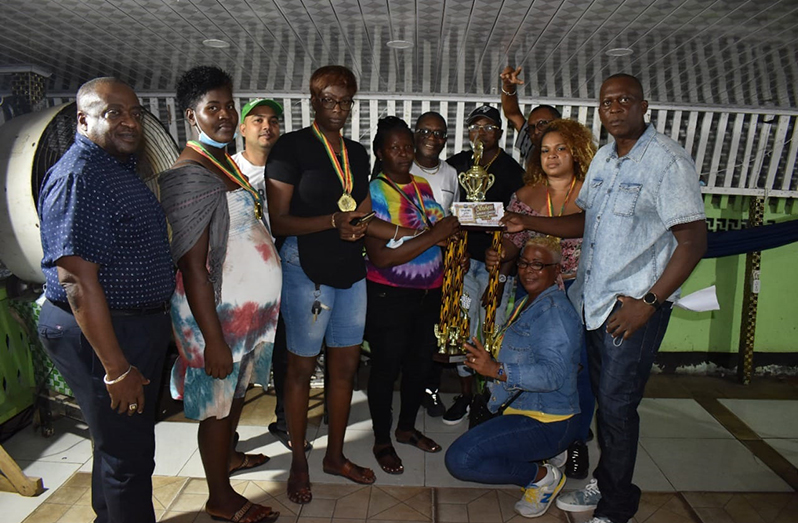 The victorious Cobras team pose with their hardware as organizer, Roderick Harry, presents the Abu Guyana winners’ trophy and cash incentive to the captain in the presence of sponsors Dynasty Sports Club, Triple M Investments, Ryan Rambalak and Raphael’s Trading Enterprise.