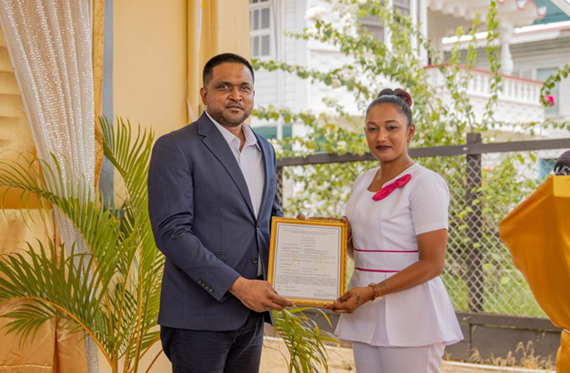 Minister of Local Government and Regional Development, Nigel Dharamlall, handing over the licence to one of the nurses of the health centre