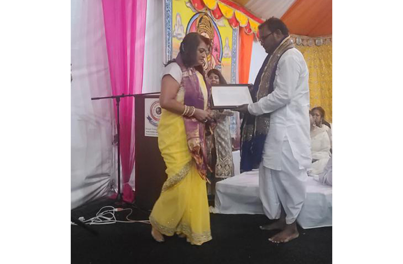 A pandit presents the certificate of recognition from New York City Mayor, Eric Adams, to Guyanese-American, Lolita Singh, last Saturday