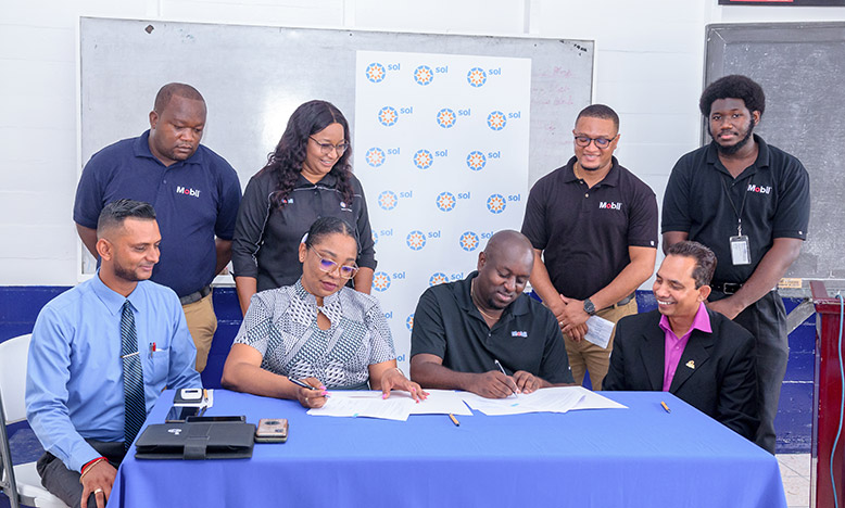 Dr. Renita Crandon Duncan, Principal of GTI (front row, second from left) and Earl Carribon, General Manager at Sol Guyana (front row, third from left) signing the agreement. Also pictured are Dr. Ritesh Tularam, Deputy Chief Education Officer (left) and staff members of Sol Guyana