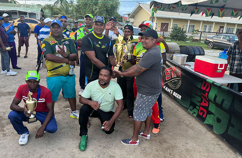ANSA McAL’s Chandradat Arjune (right) hands over the winning trophy to a representative of Fisherman in the presence of other players.