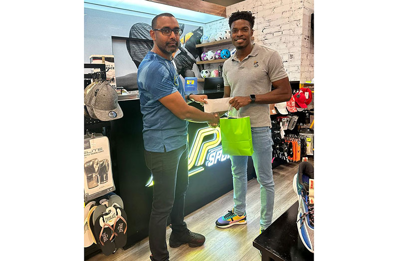 The Chief Executive Officer (CEO) of MVP Sports, Ian Ramdeo (left) hands over the endorsement package to Arinze Chance at the store’s Giftland Mall location