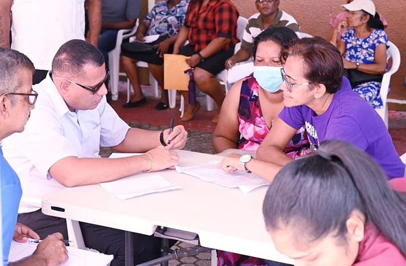Minister of Housing and Water, Collin Croal, interacts with a squatter (third from right) and a member of his team