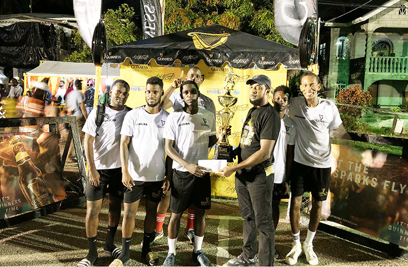 Guinness Brand Manager Jeoff Clement handing over the championship trophy to Stephon Reynolds of Liliendaal Hustlers in the presence of teammates.