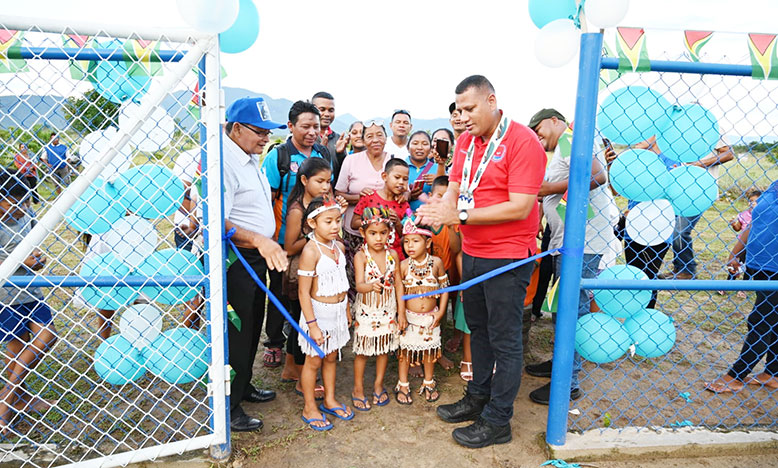 Minister of Housing and Water, Collin Croal, looks on, along with other officials and residents as a child of Parikawarinau, Region Nine, cut the ceremonial ribbon to commission the $18M water supply system