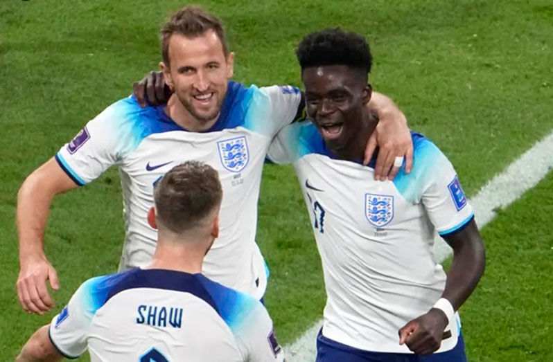 England forward Bukayo Saka celebrates with captain Harry Kane and defender Luke Shaw after scoring his side's fourth goal during their World Cup Group B game against Iran at the Khalifa International Stadium in Doha, Qatar on Nov 21