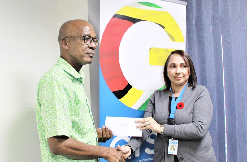 Minister of Labour, Joseph Hamilton, receives the cheque from GYSBI Human Resource Manager, Lilowtie Chintamani.