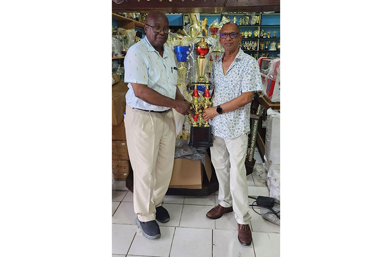 Trophy Stall proprietor, Ramesh Sunich (right), hands over the winner's Legends Over-50 trophy to the GSCL president Ian John