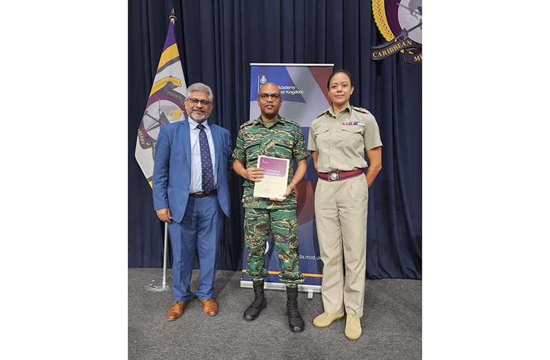 Lieutenant Colonel Eon Murray displays his certificate in the company of UK officials
