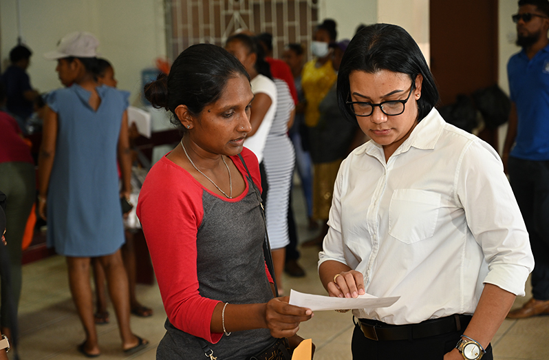 Minister within the Ministry of Housing and Water, Susan Rodrigues assists a resident of Pigeon Island
