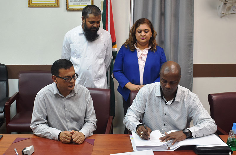 Chief Education Officer Saddam Hussain, and Education Minister Priya Manickchand overlooking the signing of the contract between Deen Kamaludeen of Deen+Partners and the Ministry’s Permanent Secretary, Alfred King (Carl Croker photo)
