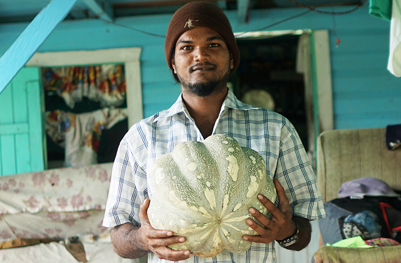 Hiriram Jairam posing with one of the pumpkins from his farm