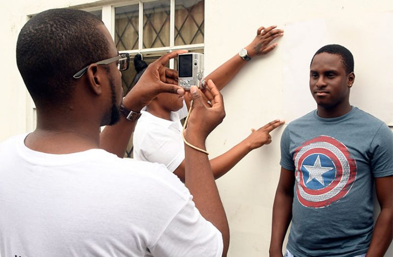 A GECOM enumerator takes a photograph of Joel Evans as a part of his GECOM’s registration process in 2019 (Adrian Narine photo)