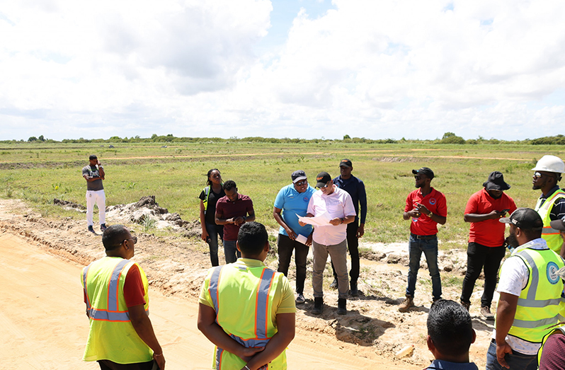Minister of Housing and Water, Collin Croal (centre), looking at the documented plan for the scheme, while in discussion with staff and contractors