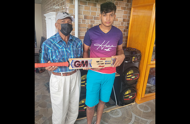 Francis Gurahoo (right) proudly displays his bat in the presence of his dad, Joseph Gurahoo.