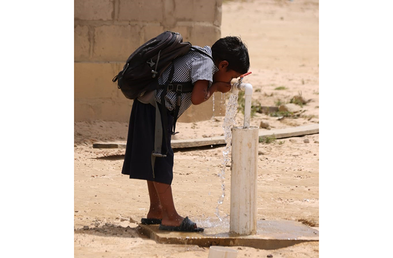 With the commissioning of a new water supply system in Kato, Region Eight, a school child enjoys the potable water system that will benefit some 450 residents