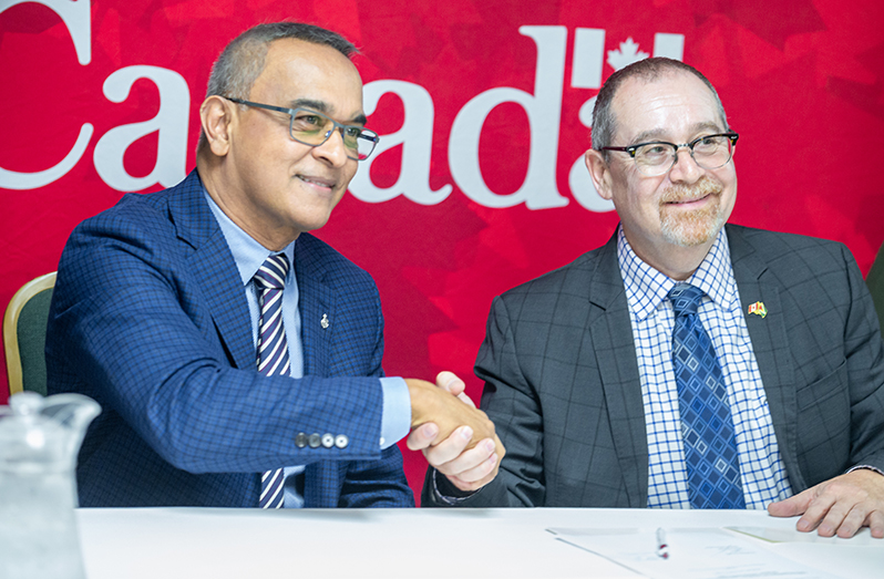 Dr. Narendra Singh, Associate Clinical Professor at McMaster University (left) and Canadian High Commissioner to Guyana, Mark Berman (right) shake hands after signing the agreement on Monday (Delano Williams photo)
