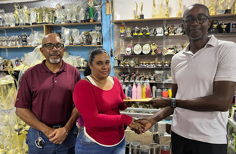 Monique Allicock - Sales Representative- South Road branch Trophy Stall, hands over the sponsorship cheque to LGC PRO Paton George in the presence of the clubs Secretary Chet Bowling.