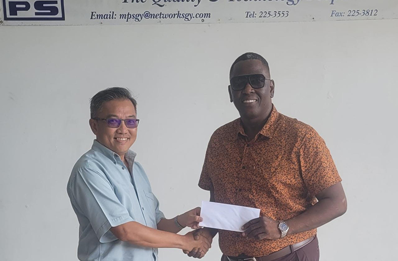 Mings Products and Services Representative, Mr. John Chin hands over cheque to Kenneth Williams