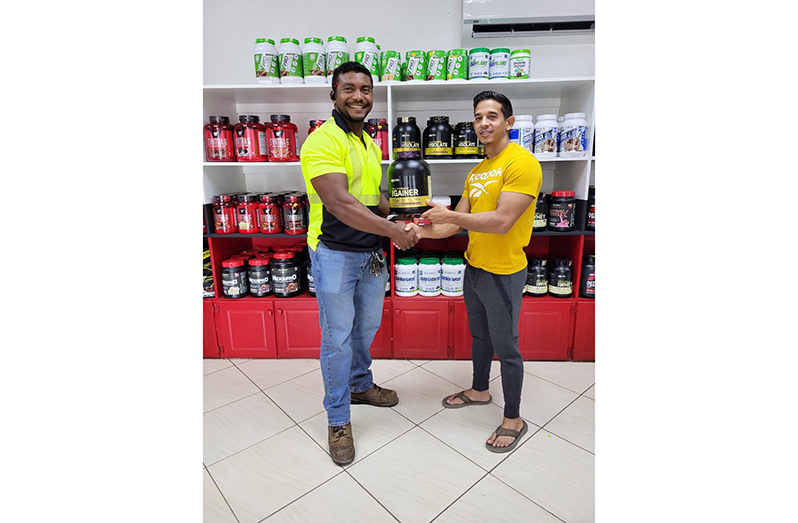 Manager of Fitness Express, Jamie McDonald hands over protein powder to Carlos Petterson-Griffith.