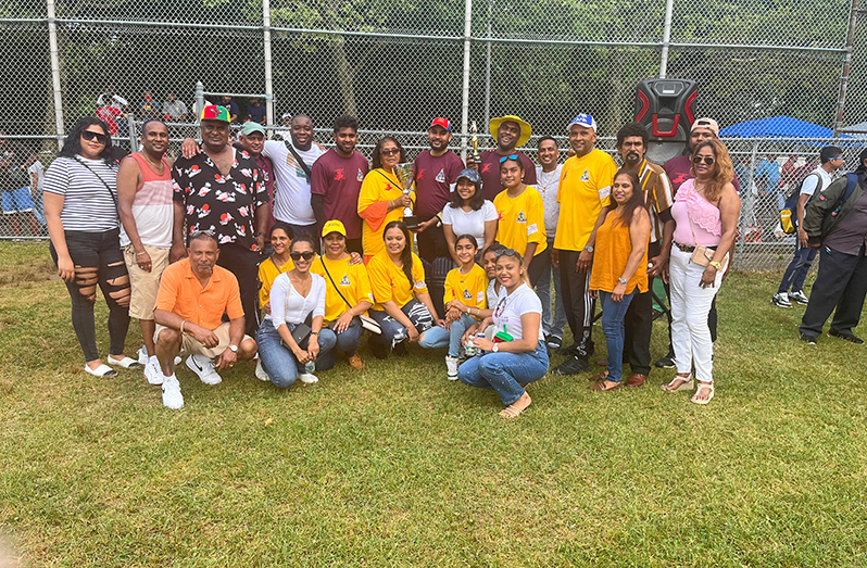 Lynette Sarjoo, wife of the late Neville Sarjoo, hands over the winning trophy to the East Bank skipper in the presence of other players and supporters. (Pictures by Frederick Halley).