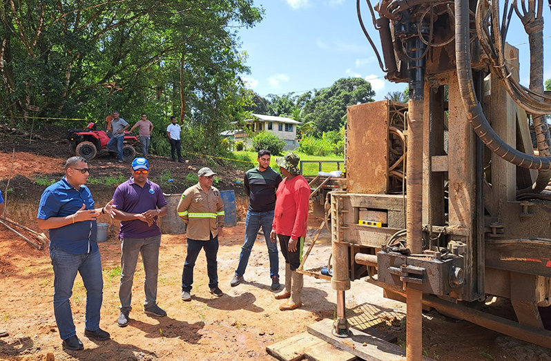 Housing and Water Minister, Collin Croal (left) makes a point to GWI Hinterland Services Director, Ramchand Jailall (second left) at the project site