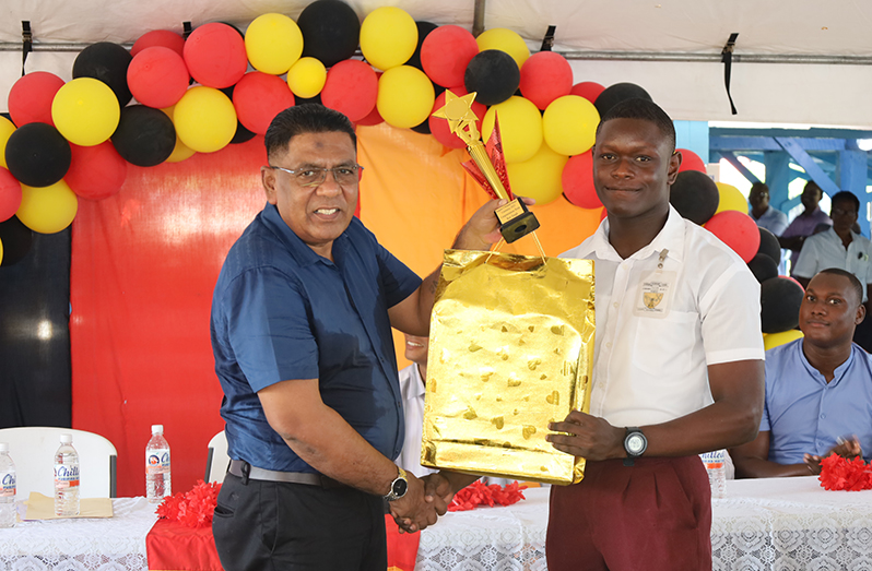 PPP/C Executive Secretary, Zulfikar Mustapha hands over several prizes to Region Five’s most outstanding CSEC student, Malique Washington