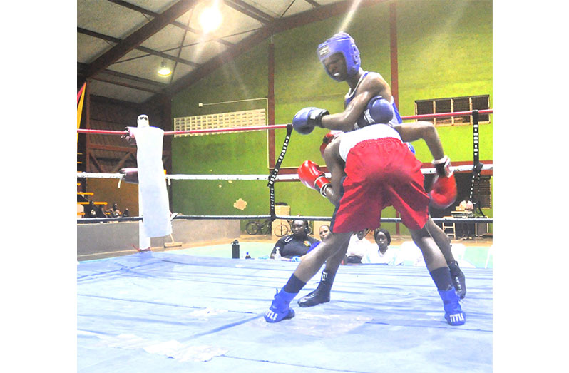 Morlando Cameron of RHJ pounds away at Police's Ronaldo Hunte (red) in the Lightweight semi-final on Saturday night at the Gymnasium (Sean Devers photo)