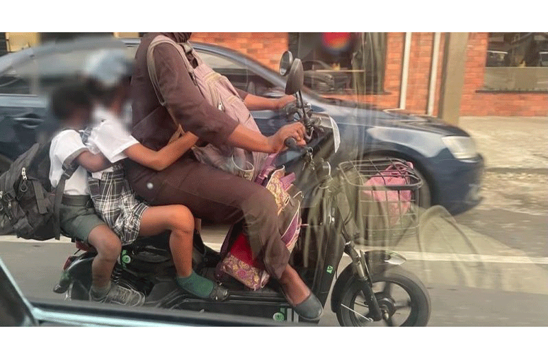 A woman riding an electric bike with her two children saddling at the back, all without helmets