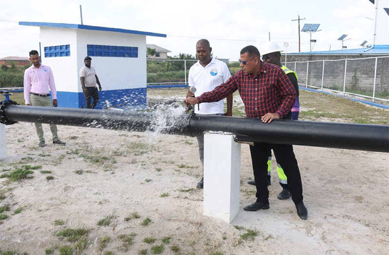 Minister of Housing and Water, Collin Croal, tests the Eccles Well in the company of GWI Staff