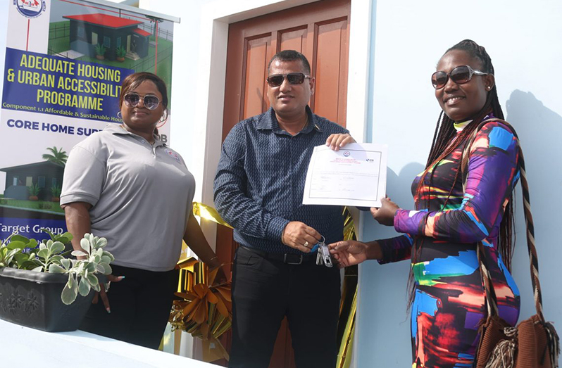 Tandasey O’Neil (right) receives the keys to her new home from Minister of Housing and Water, Collin Croal (centre), in the presence of Deputy Director of Community Development, Mrs. Donell Bess-Bascom (left)